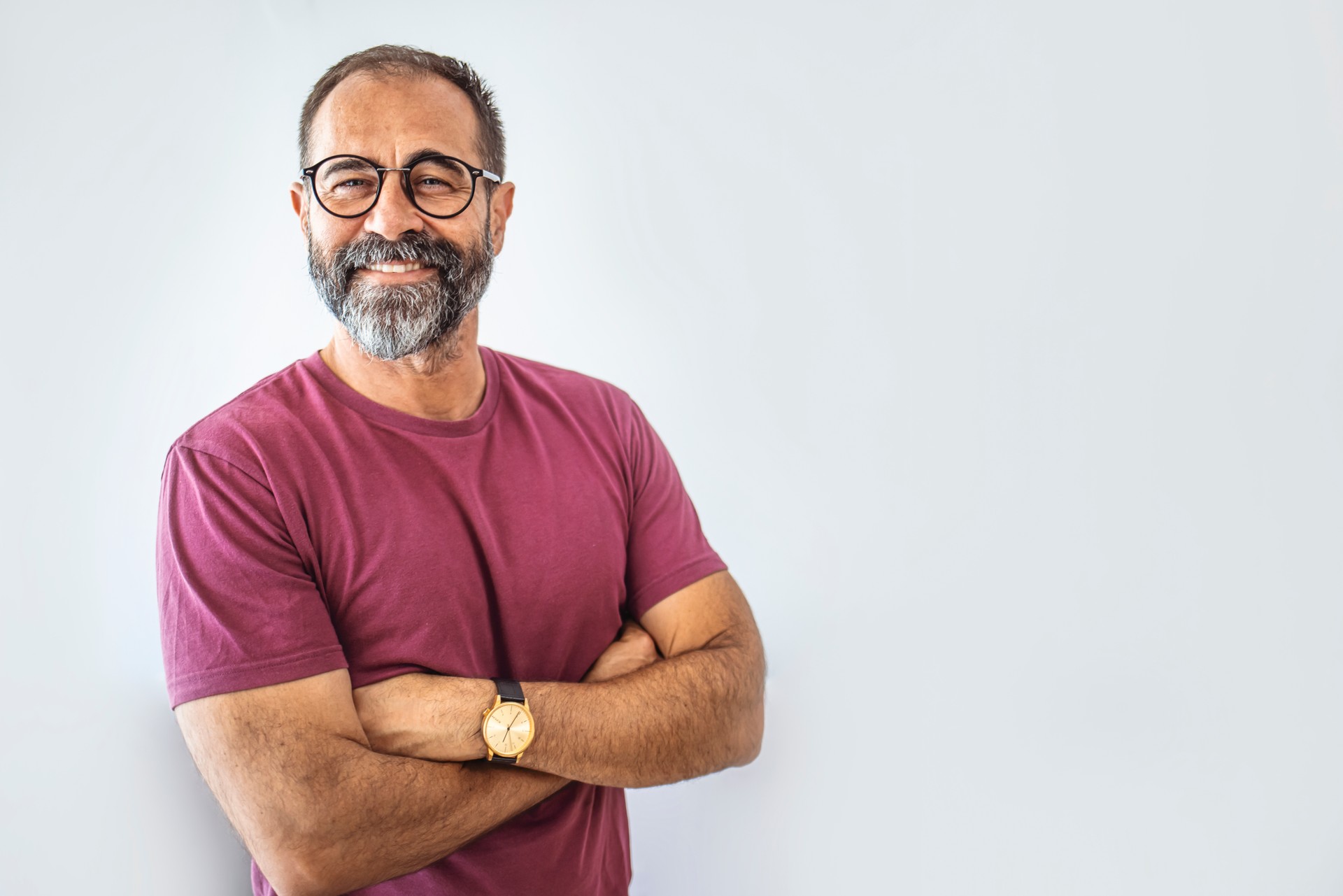 Portrait of happy mature man wearing spectacles and looking at camera indoor.